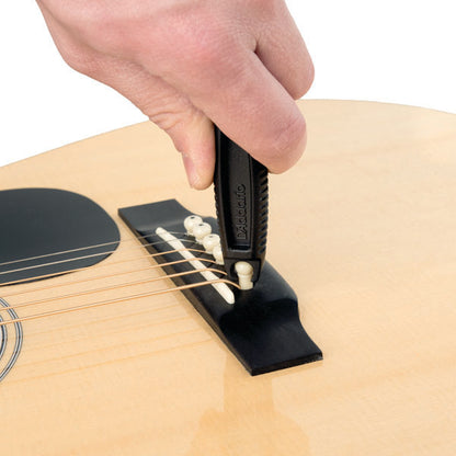 Person using a guitar tool to pull a pin off a bridge of an acoustic guitar. 