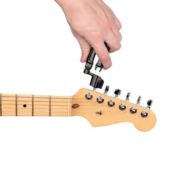 Hand using a guitar string winder on a guitar machine head with a white background
