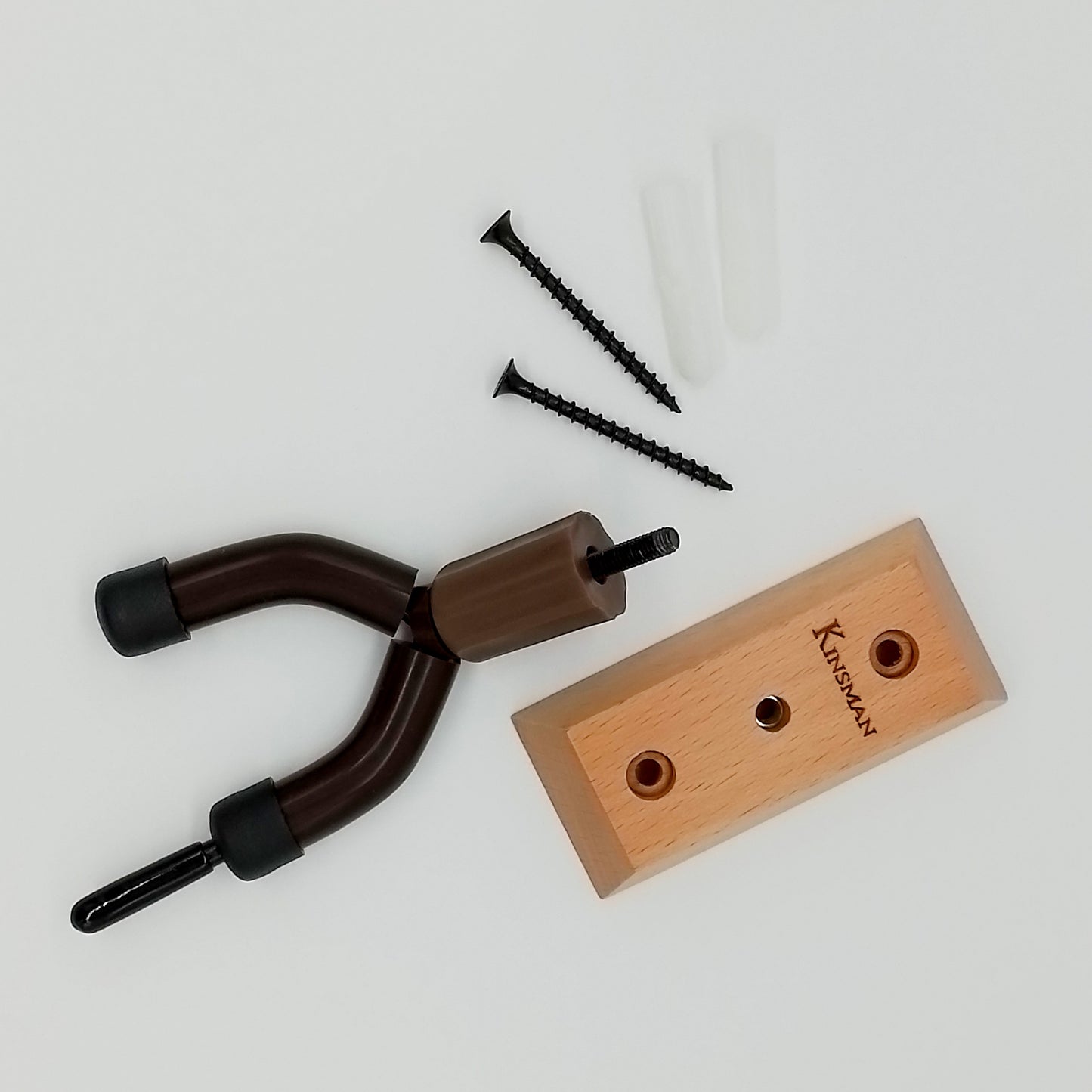 Wooden block with screw holes, metal U-shaped tool, and screws on a light gray background