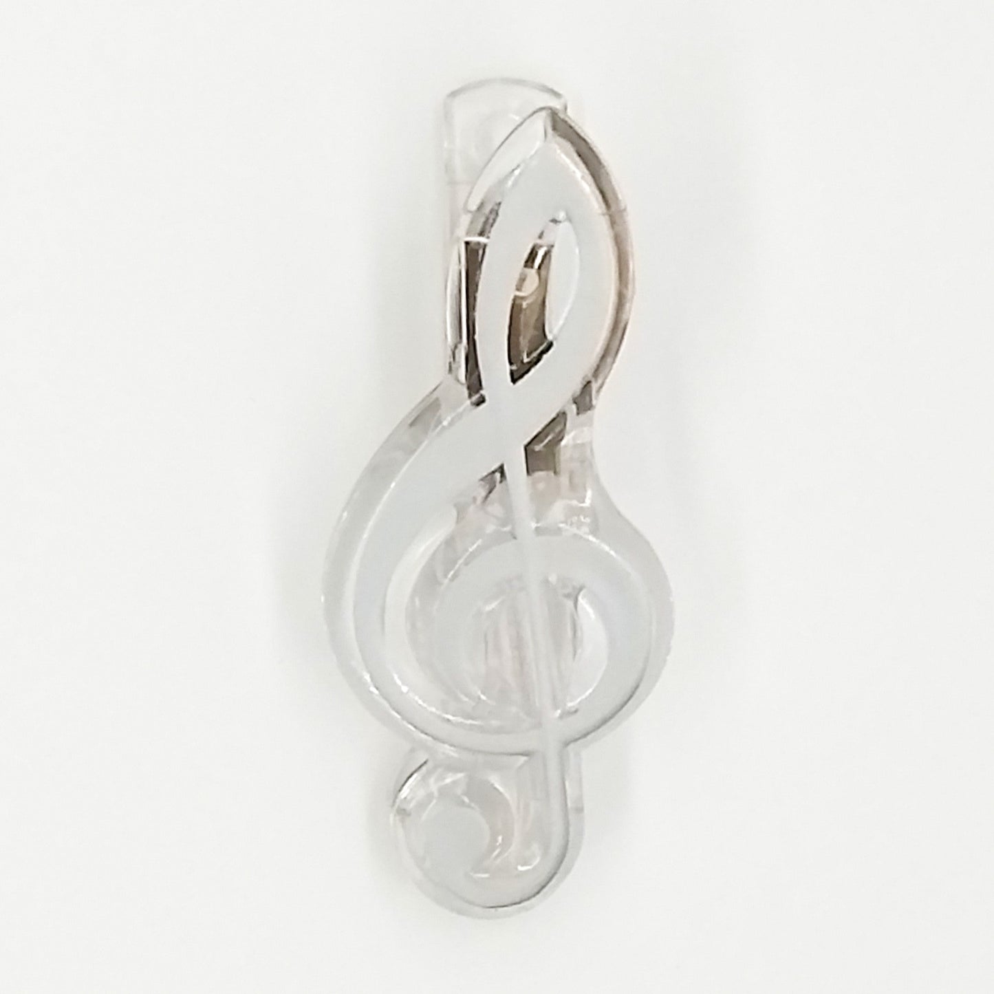 Silver treble clef paper clip on a white background