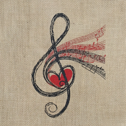 A close-up of a fabric surface in warm beige with a printed musical treble clef design in black and red, featuring a red heart and red staff lines.