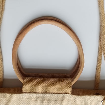 Close-up of a natural wood oval ring handle attached to a tan burlap or jute fabric strap on a light gray background.