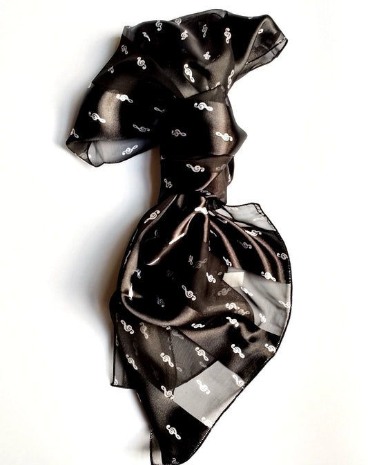 A black sheer mesh scarf with a small white treble clef pattern, tied in a knot and draped on a white background.
