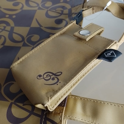 A beige  phone pouch with a treble and bass clef logo, featuring a snap-button closure and a black brand tag, resting on a patterned bag.