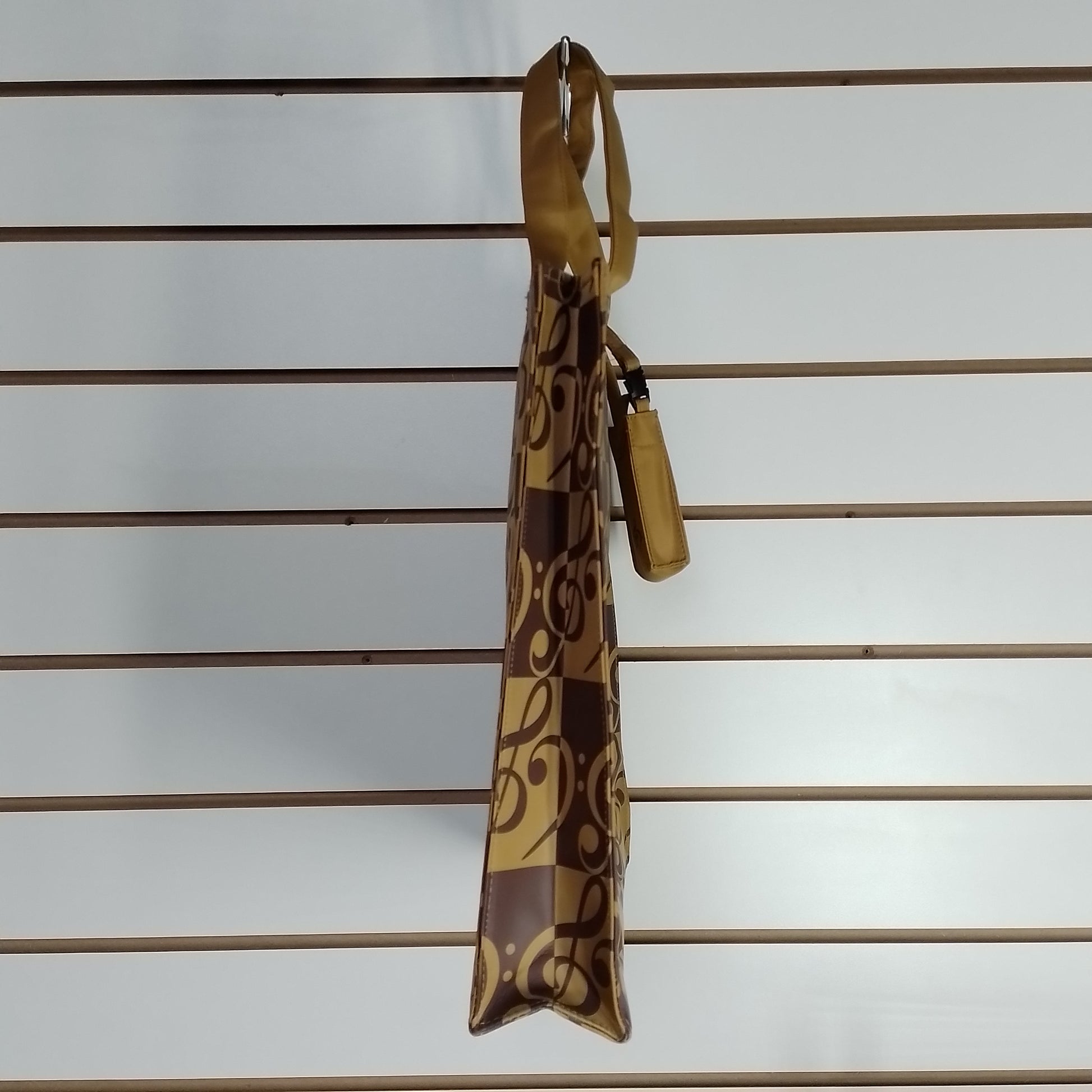 A brown and tan patterned bag with a matching leather tassel, hanging from a slatwall display.
