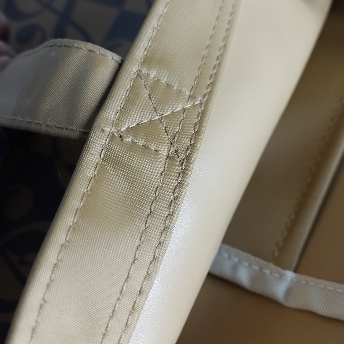 Close-up of a beige fabric strap with decorative diagonal stitching and a small embroidered star detail.