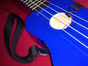 Blue ukulele with a strap on a red background