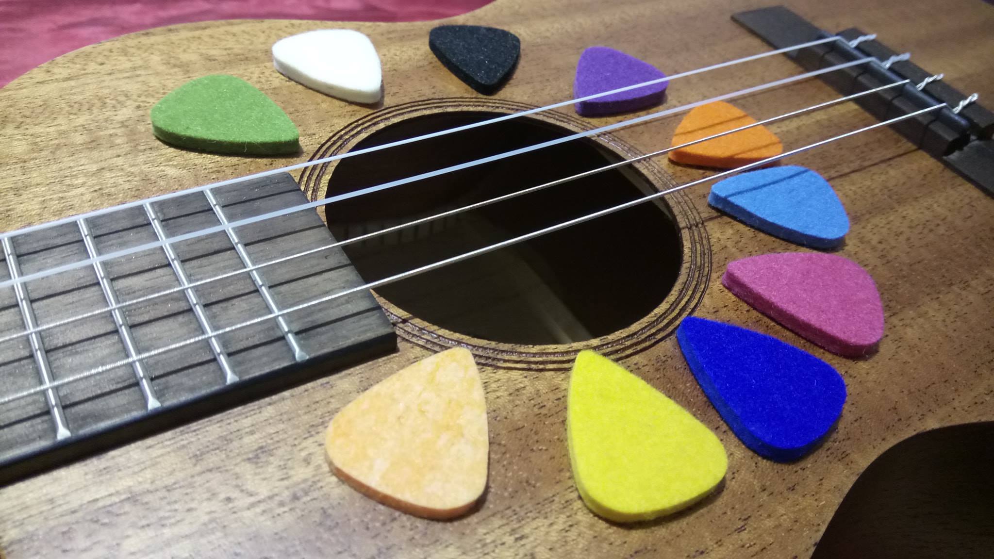 Close-up of a ukulele with colorful guitar picks on the sound hole