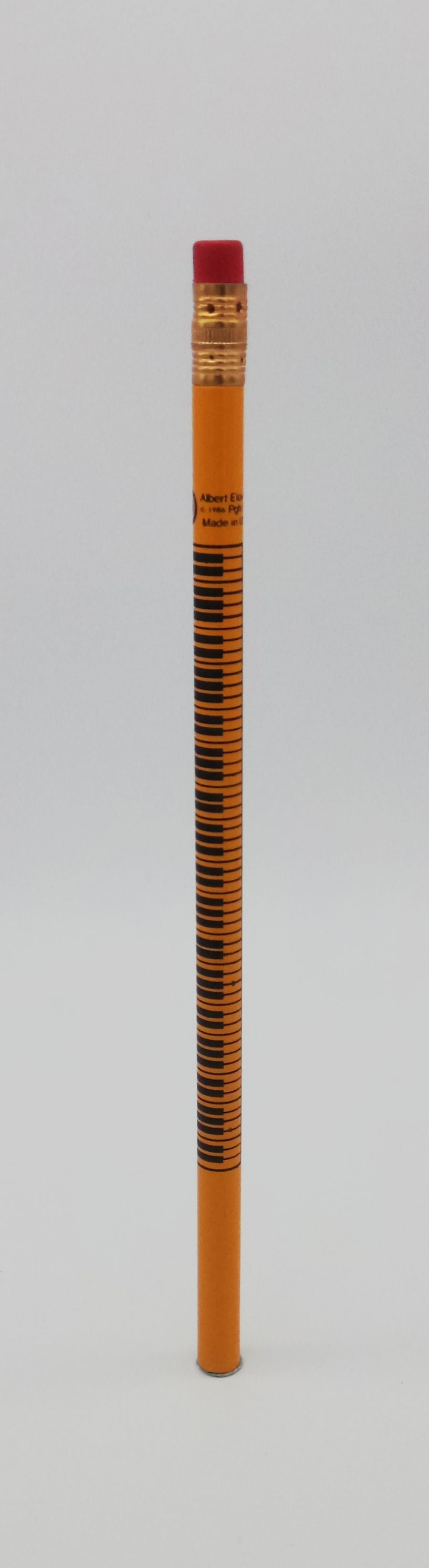 Pencil with piano keys a red eraser on a grey background