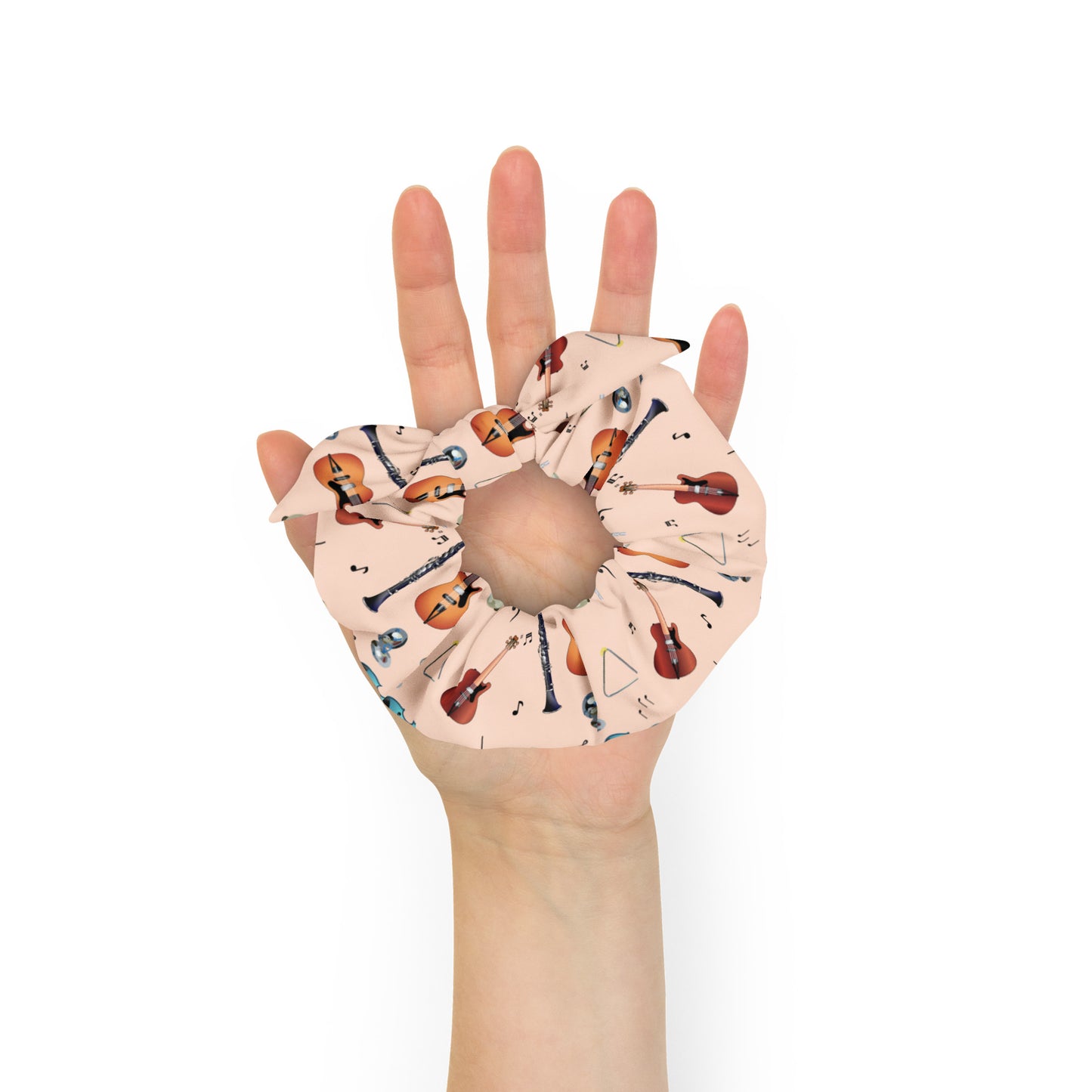 Hand wearing a scrunchie with musical instrument pattern on a white background