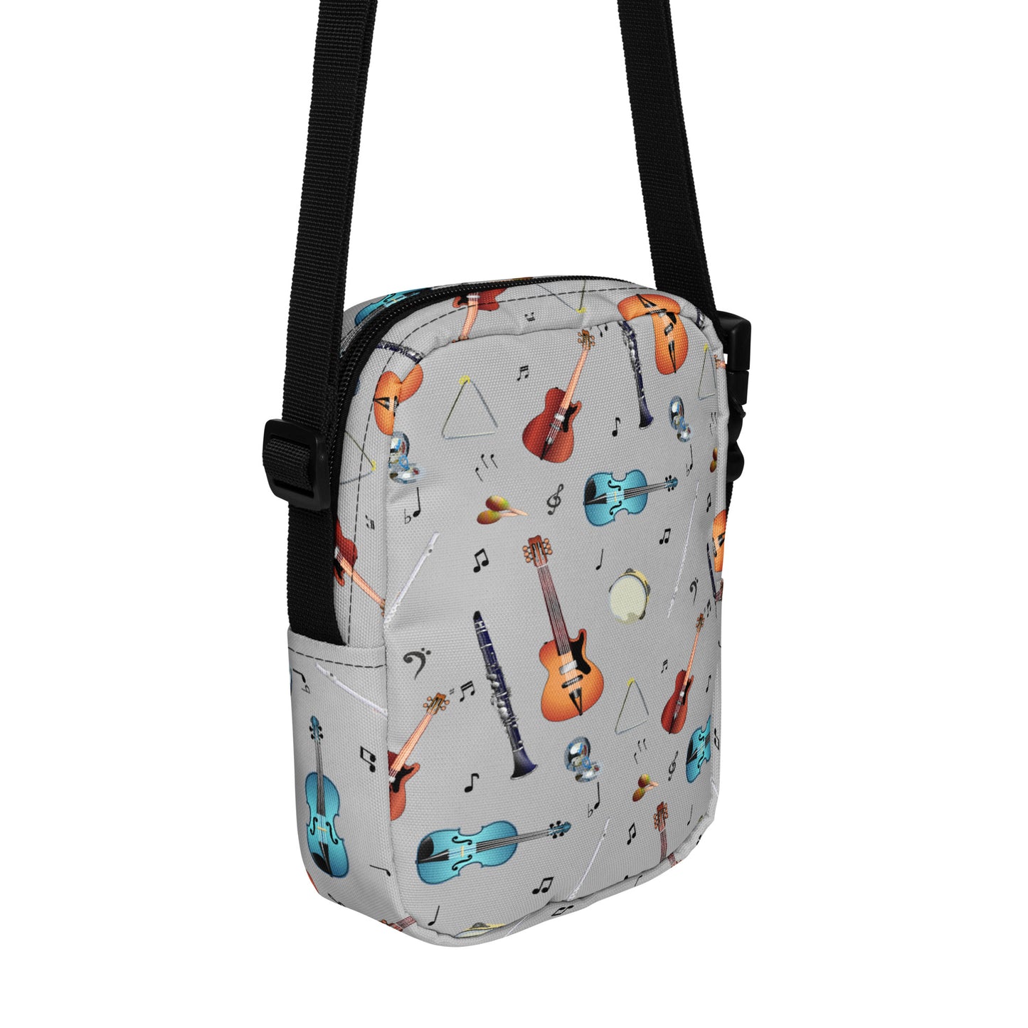 Grey crossbody bag with black adjustable shoulder strap (with black plastic clip), inside and outside pockets, sturdy fabric, and two-way zipper. The design features a repeat pattern of colourful musical instruments and black musical notes on a grey background.