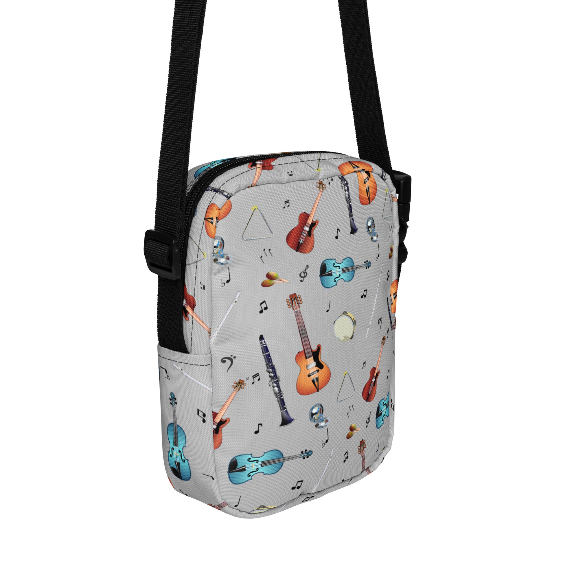 Grey crossbody bag with black adjustable shoulder strap (with black plastic clip), inside and outside pockets, sturdy fabric, and two-way zipper. The design features a repeat pattern of colourful musical instruments and black musical notes on a grey background.