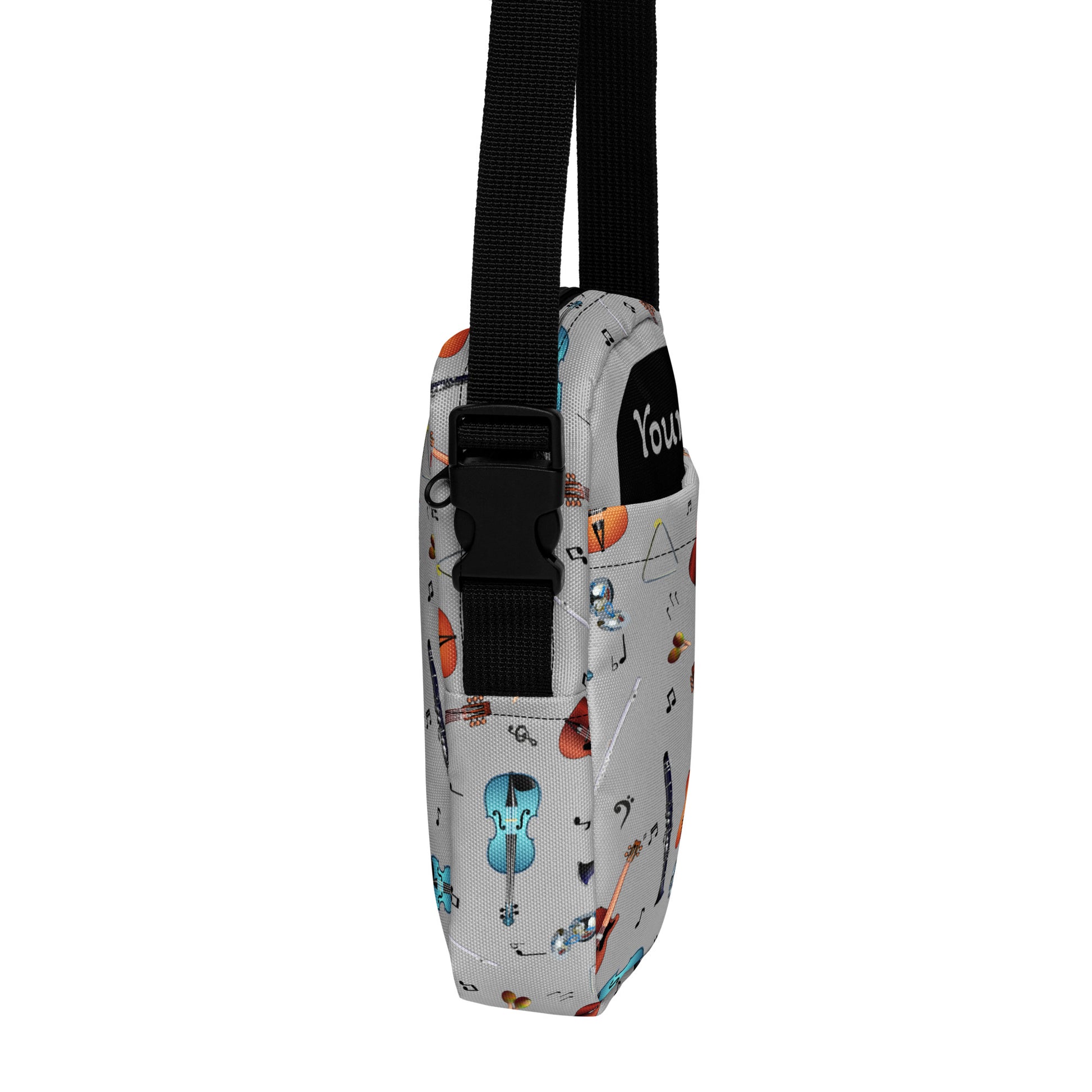 Grey crossbody bag with black adjustable shoulder strap (with black plastic clip), inside and outside pockets, sturdy fabric, and two-way zipper. The design features a repeat pattern of colourful musical instruments and black musical notes on a grey background.