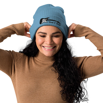 Woman wearing a blue beanie with text, smiling against a white background