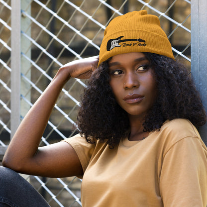 Woman wearing a mustard yellow beanie and shirt against a chain-link fence background