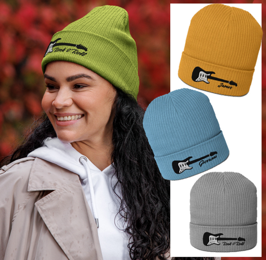 Woman wearing a green beanie with a guitar design, surrounded by additional beanies in yellow, blue, and gray.